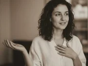 Anna deutet mit der rechten Hand nach oben.